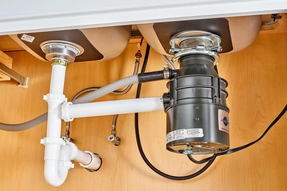 Close-up of a garbage disposal with dishwasher drain hose connection