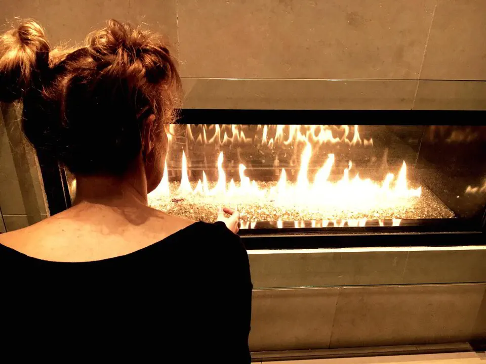 Technician testing the gas valve and pilot assembly on a gas fireplace