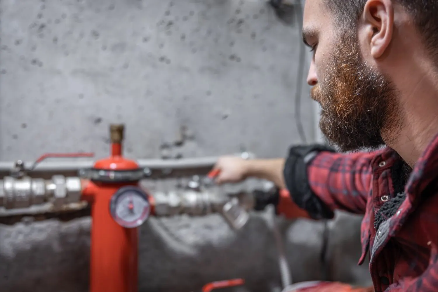 Plumber installing black iron natural gas pipe in a Stark County basement